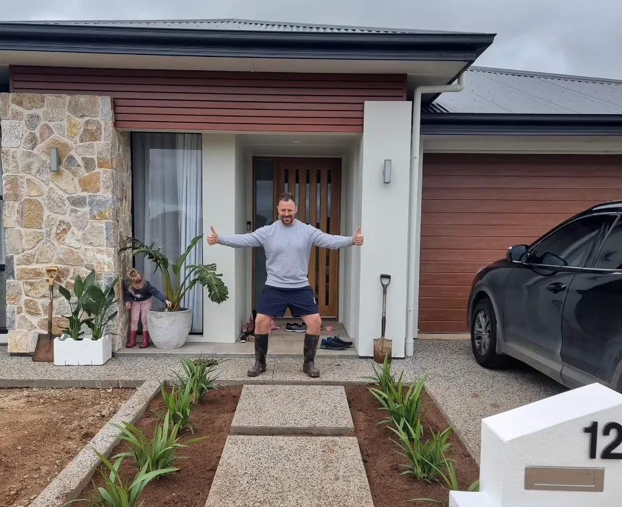 A home owner with arms outstretched at the front door of a new house
